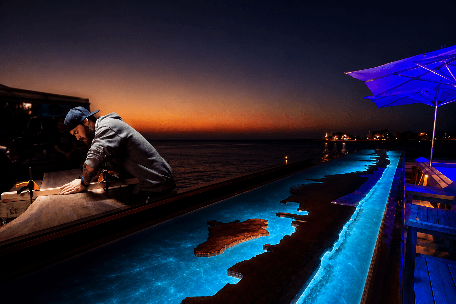 Live edge bar top glowing teal over the bay at night