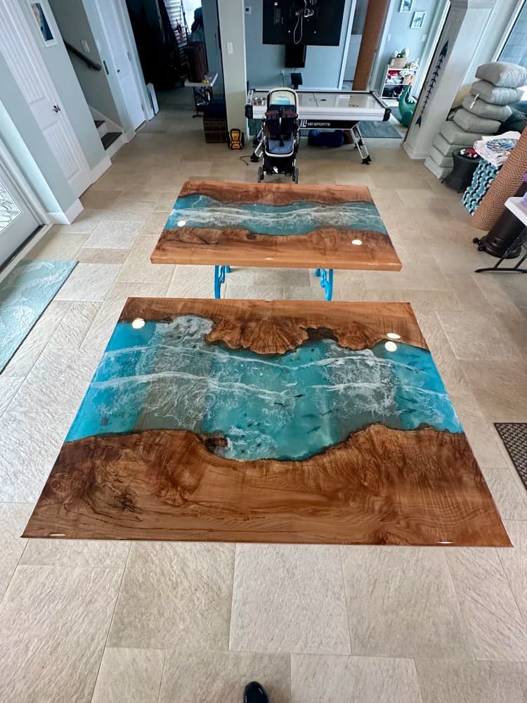 Two ocean wave epoxy table tops on the floor