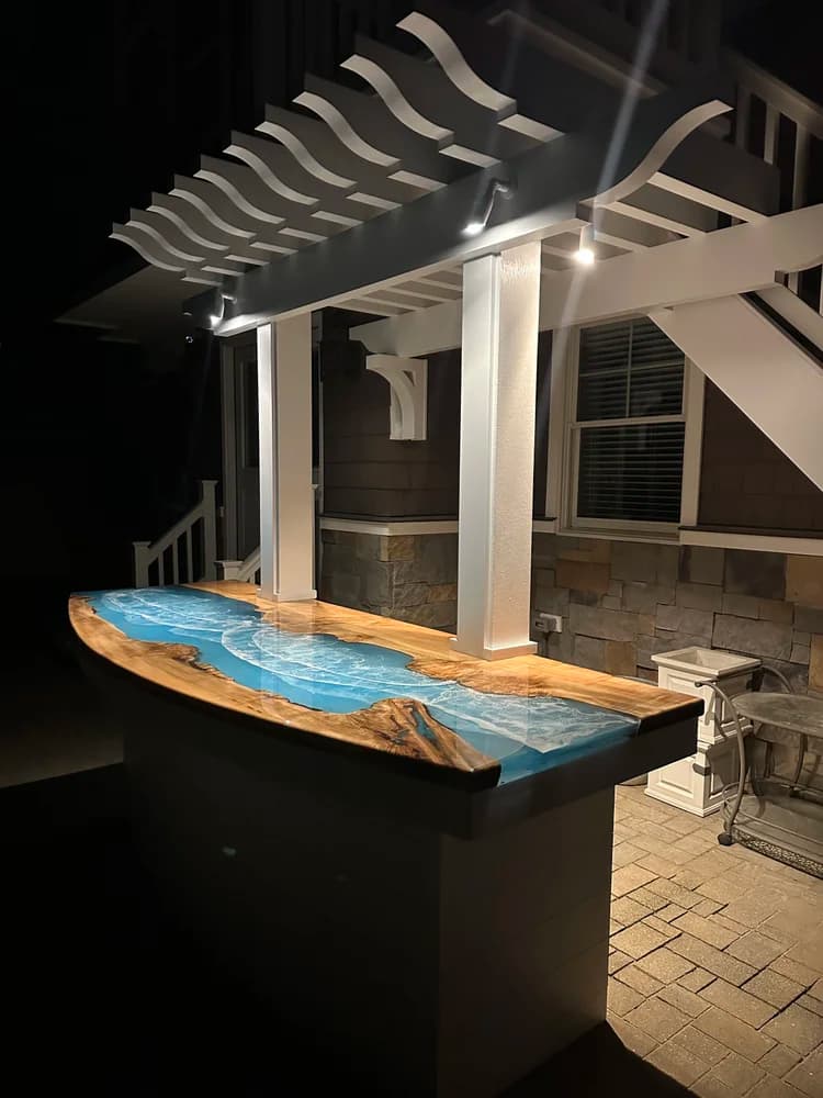 Outdoor pergola bar top with teal epoxy lit up at night