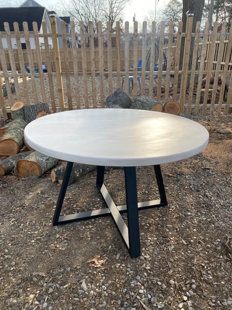 White washed round table with black X-base steel legs